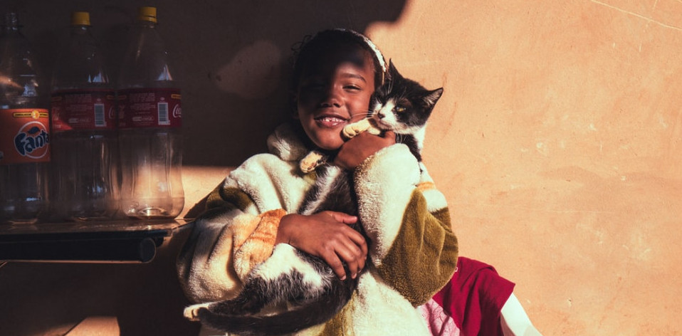 Child smiling and cuddling up with a happy cat