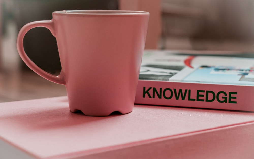 Coffee mug by a book that says 'knowledge'